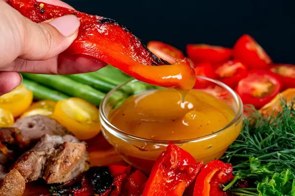 Grilled bell pepper with mango sauce in a female hand, close-up