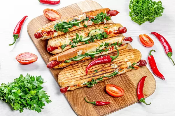 Grilled hot dogs with fresh vegetables, herbs and chili peppers