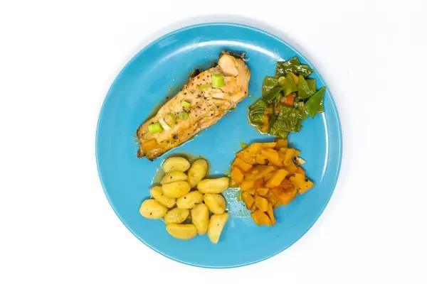 Grilled Salmon-steak in Hoisin-Miso sauce with pumpkin-sugarsnap stew and gnocchi viewed from top on white background