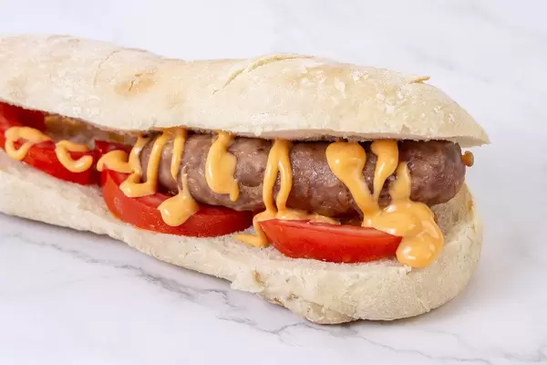 Grilled Sausage in bread with tomato on the white background (Flip 2019)