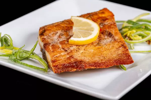 Grilled tuna steak with a slice of lemon on a white plate