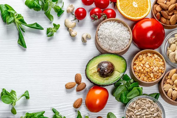 Groats, nuts, seeds, vegetables and fresh greens on a white wooden background. Top view