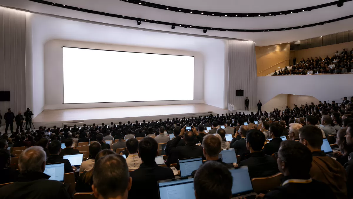 Große Konferenz mit Publikum vor hellem Präsentationsbildschirm