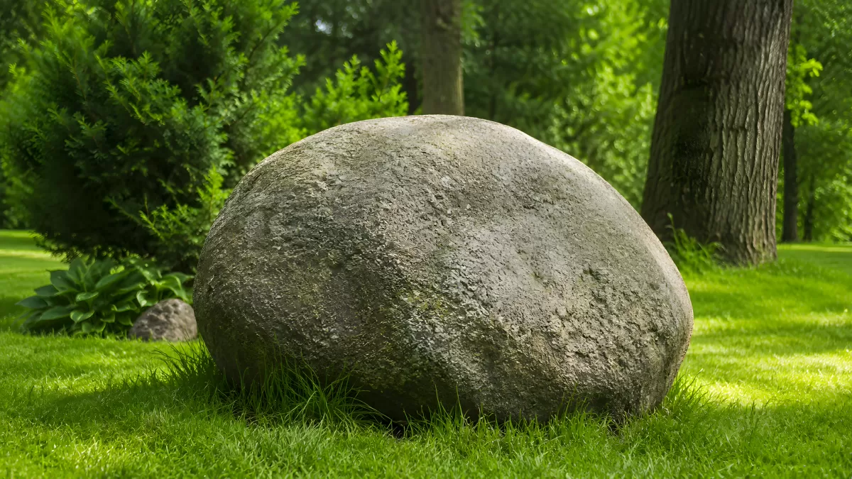 Großer runder Findling auf grünem Rasen im Garten