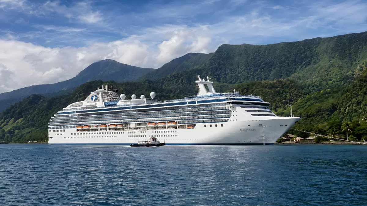 Großes Kreuzfahrtschiff vor tropischer Bergkulisse
