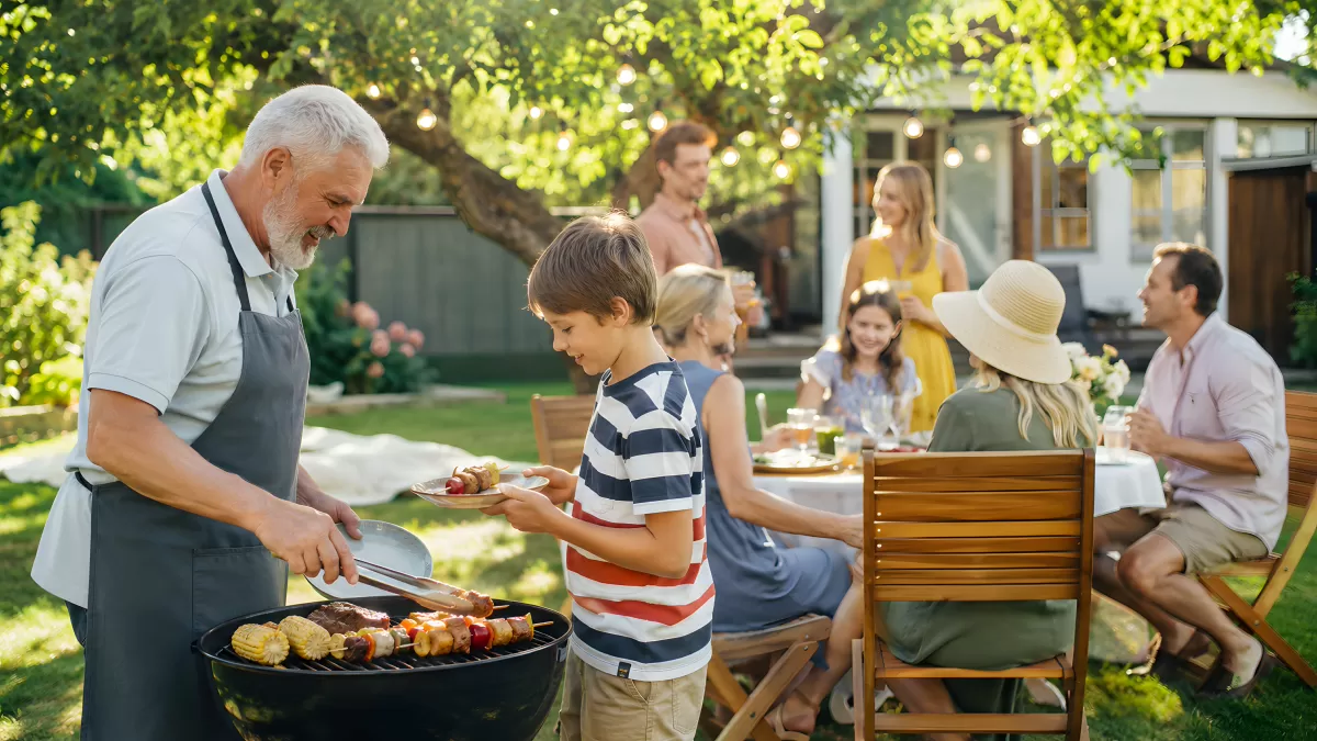 Großvater grillt mit Enkel beim Familienfest im Garten