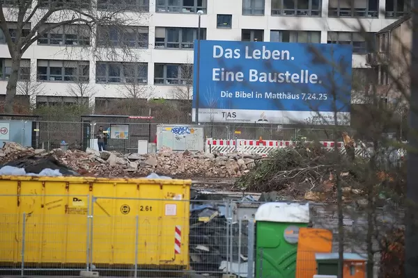 Große Baustelle vor einem Gebäude mit dem Schild "Das Leben. Eine Baustelle. Die Bibel in Matthäus 7,24.25"