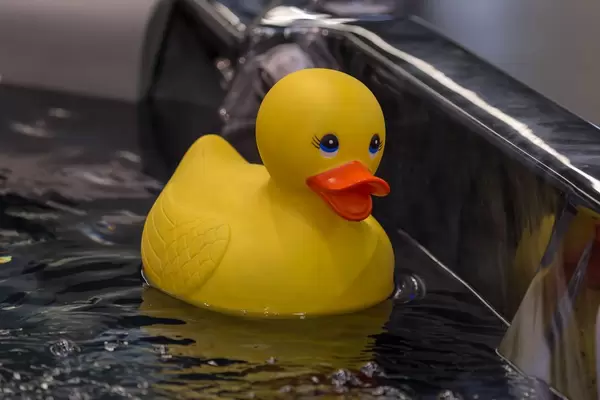 Große gelbe Badeente in dunkler Badewanne
