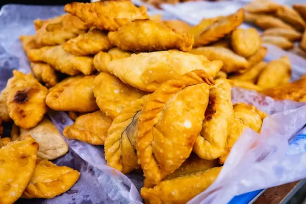 Große Menge von gebackten Empanada auf Backpapier in einem blauen Kuchenblech