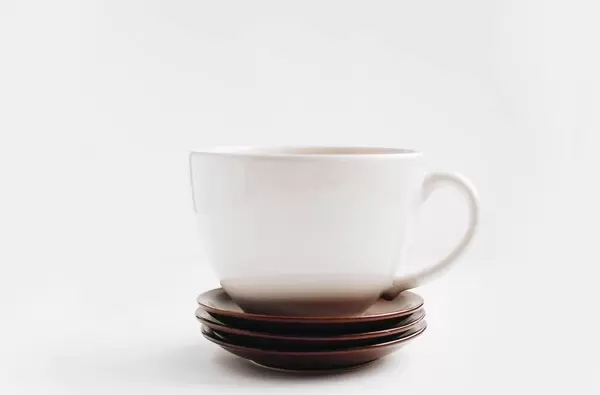 Große weiße Tasse und Nachtischteller vor weißem Hintergrund