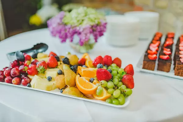 Großer Obstteller mit Erdbeeren, Ananas, Orangen Und grünen Weintrauben