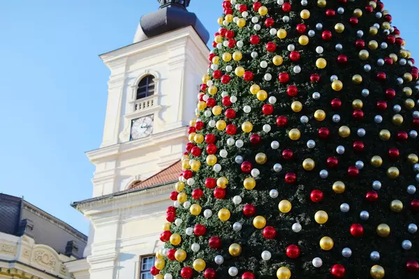 Großer Weihnachtsbaum mit roter, weißer und goldener Deko auf einem Platz an einem sonnigen Tag