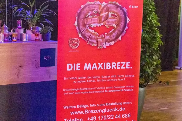 Großes rotes Schild mit Werbung für die Maxibreze bei der Bits & Pretzels Konferenz in München