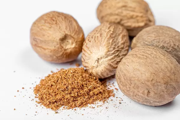Ground nutmeg and whole on white background, close up (Flip 2020)