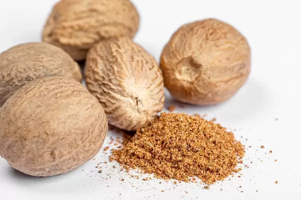 Ground nutmeg and whole on white background, close up