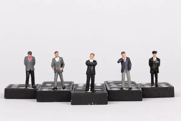 Group of businessman people standing on dominoes with white background