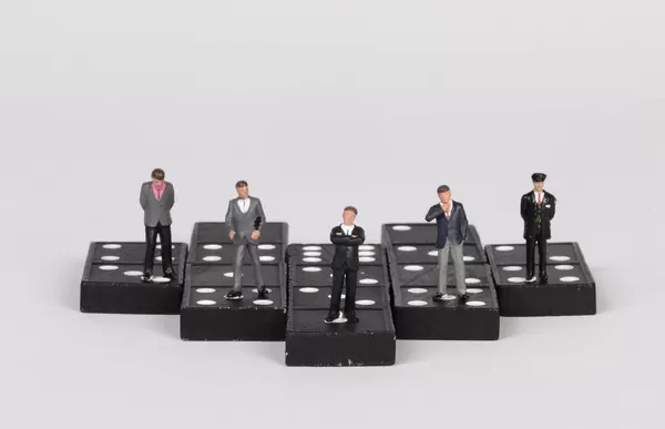 Group of businessman people standing on dominoes