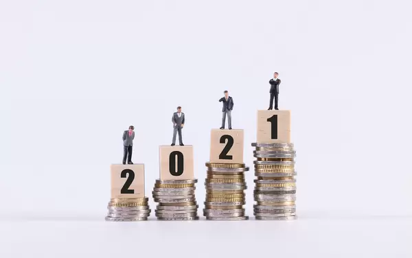 Group of businessman, stack of coins and wooden cubes with 2021 text