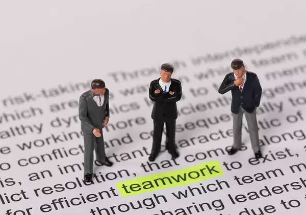 Group of businessman standing next to a word teamwork highlighted in yellow