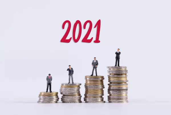 Group of businessman standing on stack of coins with red 2021 text