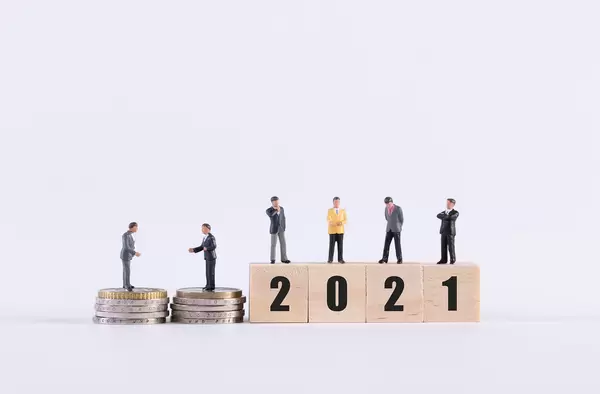 Group of businessman with coins and wooden cubes with 2021 text