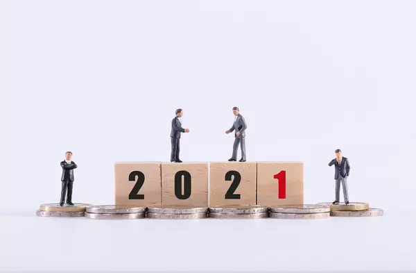 Group of miniature businessman with 2021 text on wooden cubes on white background
