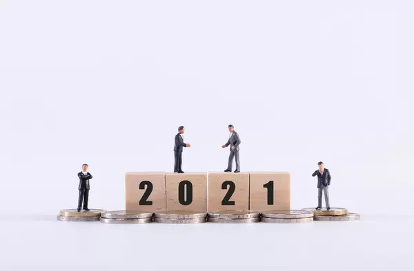 Group of miniature businessman with 2021 text on wooden cubes