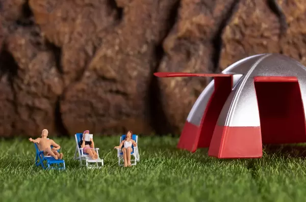 Group of miniature people relaxing in deckchairs in the nature