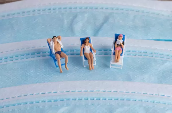 Group of miniature people sunbathing in deckchairs