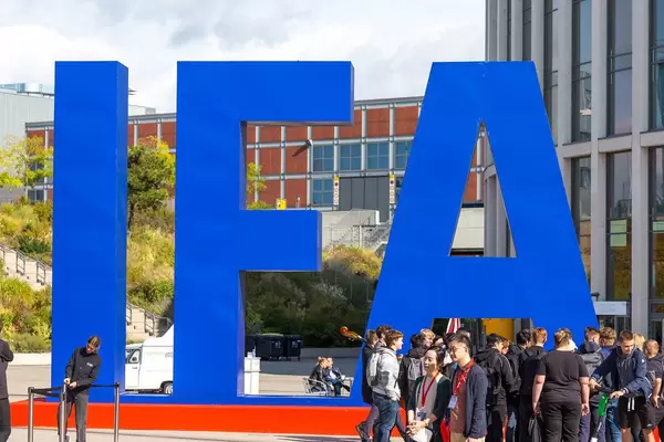 Group of people gathers in front of the blue IFA logo for the exhibition in Berlin