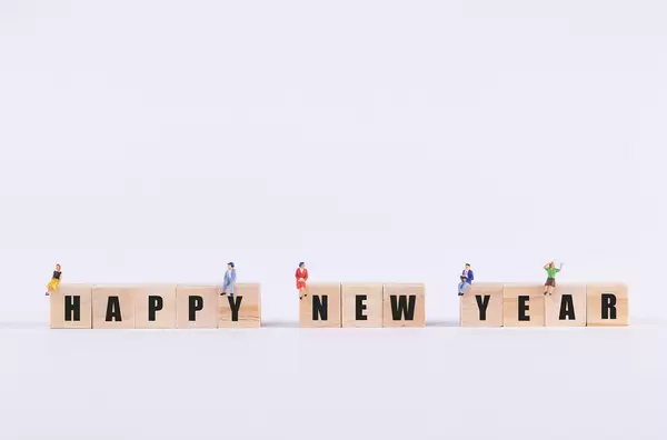 Group of people sitting on wooden cubes with Happy New Year text