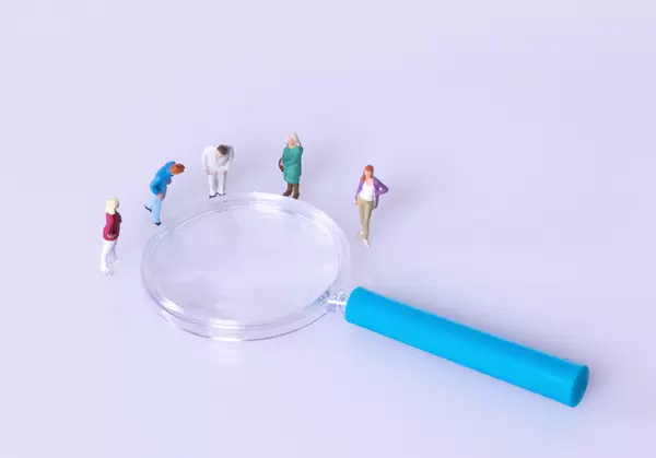 Group of people standing around magnifying glass