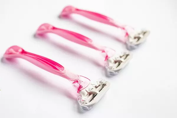 Group of three pink razors on white background