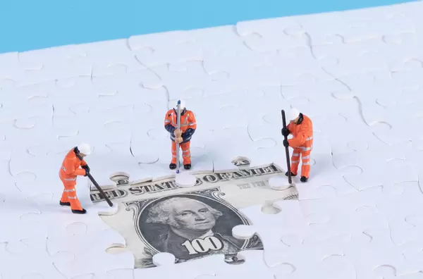 Group of workers with missing jigsaw puzzle pieces over money dollar background