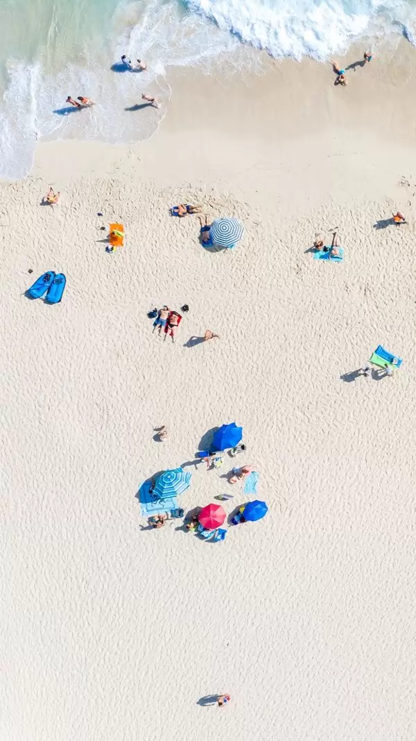 Groups, families and couples lying on the beach of Cala Mesquida in Mallorca. Drone photo