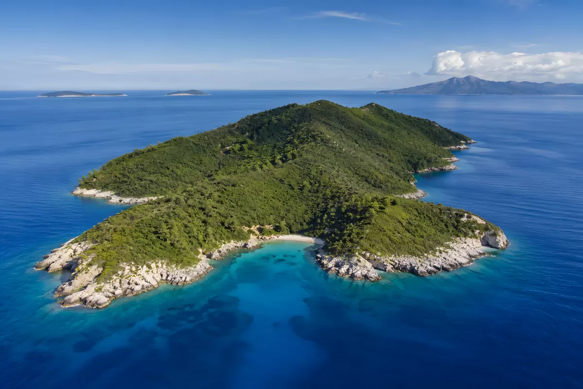 Grüne Felseninsel im türkisblauen Mittelmeer aus der Vogelperspektive