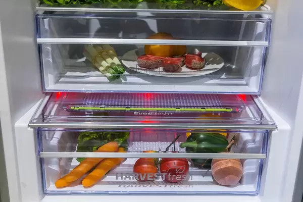 Grundig fridge with illuminated HarvestFresh drawer, filled with fruits and vegetables