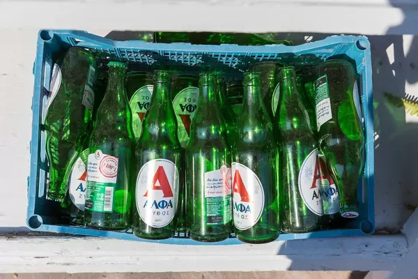 Grüne, griechische Bierflaschen in einem Plastikkorb
