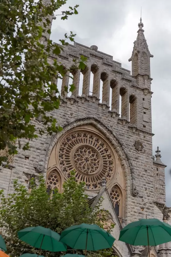 Grüne Regenschirme vor der Església de Sant Bartomeu. Römisch-katholische Pfarrkirche in Sóller