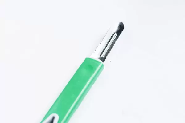 Grüner Schäler vor weißem Hintergrund. Küchenutensil