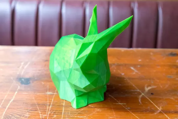 Grünes Häschen als 3D-Druck, auf einem alten Holztisch