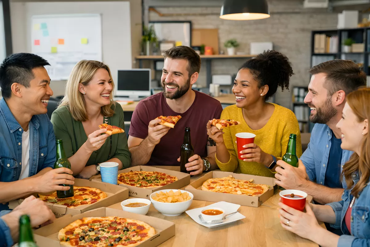 Gruppe junger Leute genießt Pizza und Getränke in entspannter Büroumgebung