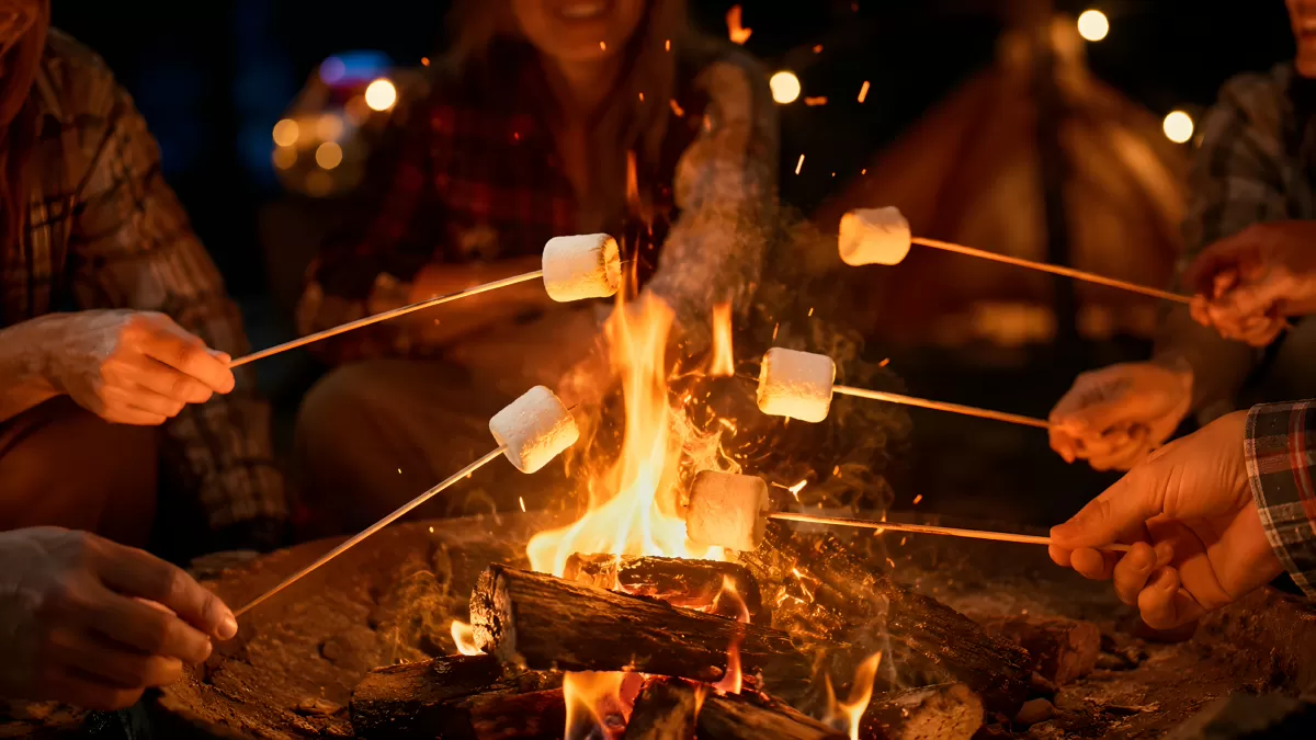 Gruppe röstet Marshmallows am lodernden Lagerfeuer