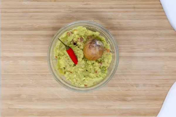 Guacamole Brotaufstrich in Glasschale auf Holztisch von oben fotografiert