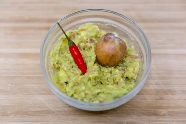 Guacamole in Glasschälchen mit Chilischote und Avocadokern