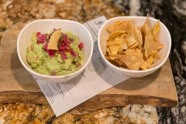 Guacamole - Nachtisch im Fit Kitchen Restaurant in Barcelona, Spanien, wird auf einem rustikalen Holzbalken mit Tortilla Chips serviert