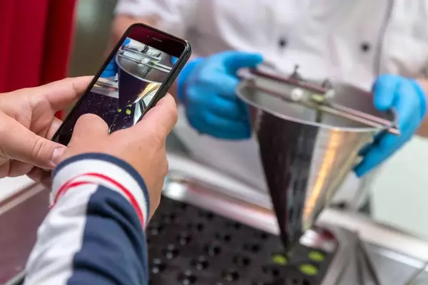 Guest photographing the preparation of Wasabi–Pea Spheres at Chino Latino restaurant