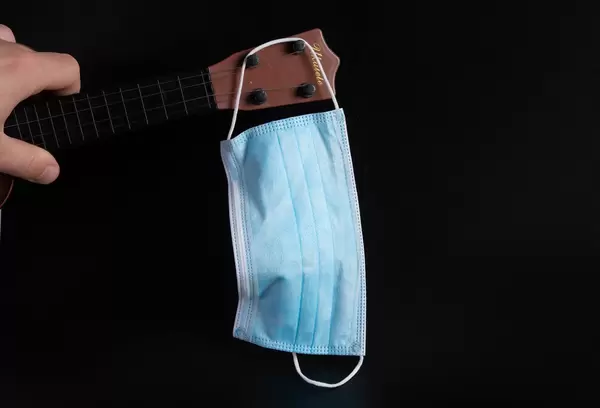 Guitar neck and medical face mask on black background