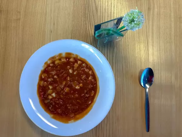 Gulasch mit Kartoffeln und Paprika in Suppenteiler mit Löffel auf Holztisch