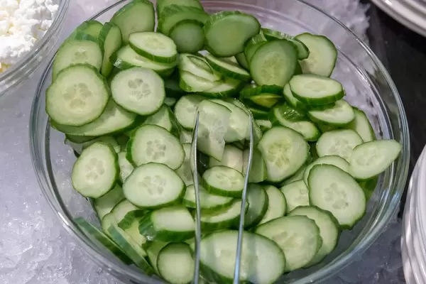 Gurkenscheiben in einer Glasschale mit Salatzange, auf einem Büfetttisch